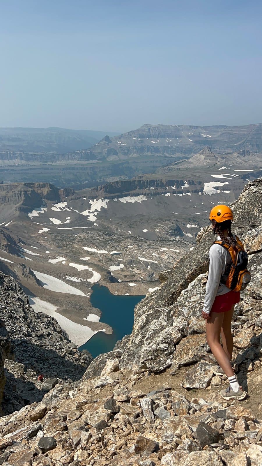 Hiker in Sierra Shorts on a rocky ridge above a snowfield